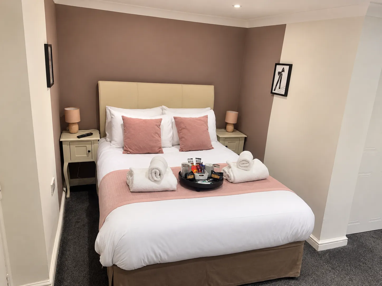 Room 3 double bed with blush cushions and a soft accent wall